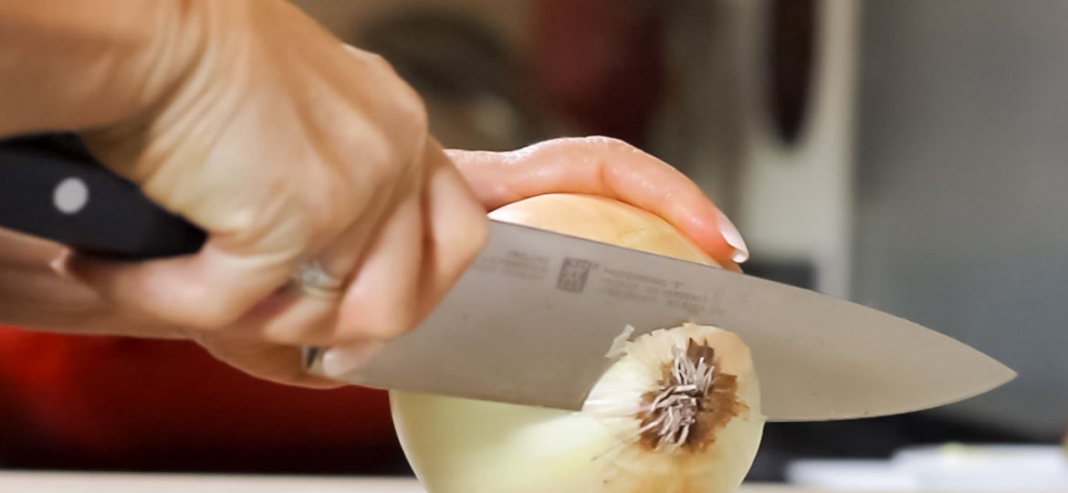 Using the Henckels Professional Chef Knife, cut the root end off leaving enough root to hold the onion together