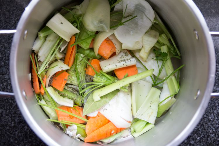 Overhead view of a stock pot with Mirepoix vegetables, herbs and spices