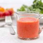 Glass cup with spout containing Bright Summer Oil-free Tomato Salad Dressing in an elegant glass pouring vessel.