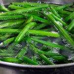 Pot of simmering water with green beans showing how blanching green vegetables keeps the color vibrant green.