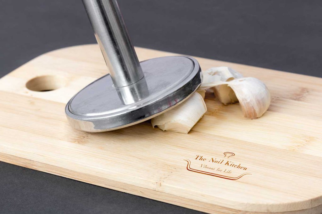 Garlic cloves on a cutting board. Tap the garlic cloves to remove the outer paper skin