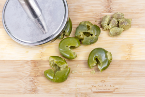 Pounder, pitted olives on a cutting board with The Noil Kitchen logo