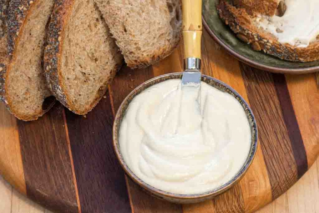 #10 Luscious Oil-free Vegan Butter swirled in a small bowl served with whole grain bread on a wooden board