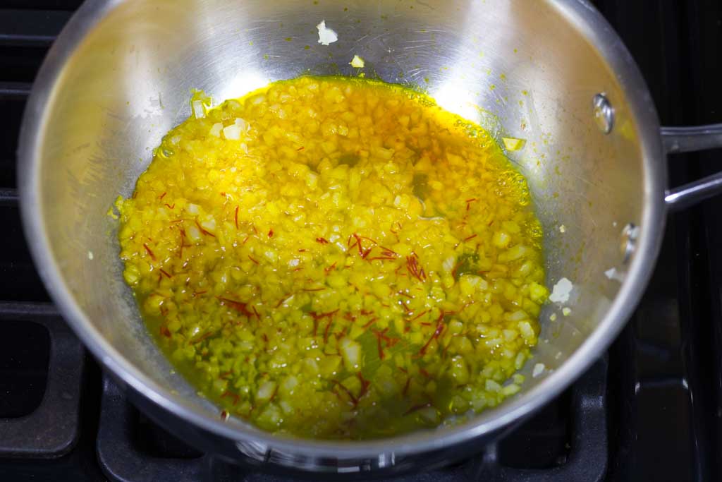 Pour in the saffron water and threads into the pan with the onions and lemon.