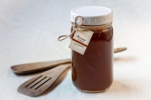 Mason jar filled with Caramelized Mushroom Stock, and a date and title tag on the jar next to 2 wooden spatulas o