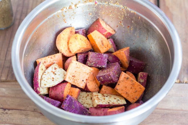 Sweet potatoes in a prep bowl after tossing with spices