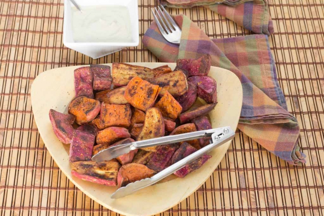 Oil-free spiced and roasted sweet potatoes in a bamboo serving dish with an oil-free aioli