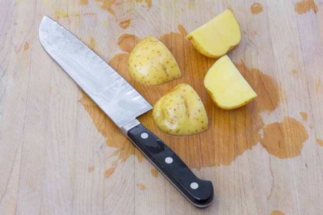 Cutting board with Santku knife and potatoes cut into smaller pieces