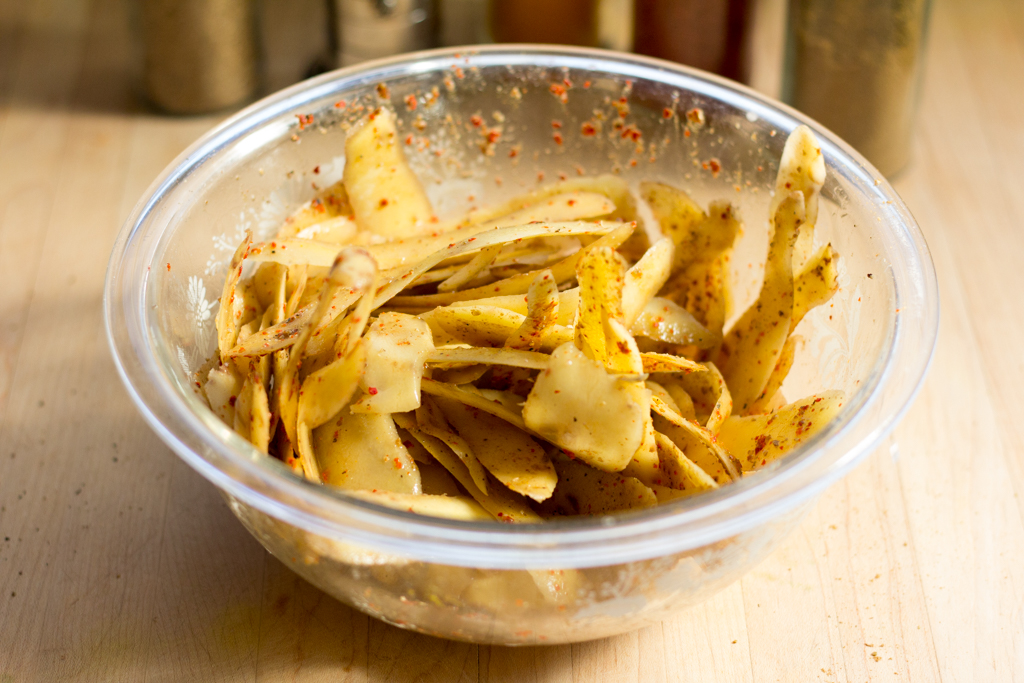 potato peels in a glass prep bowl tossed with spices and vinegar