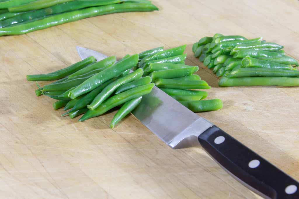 Green beans cut as desired on a cutting board