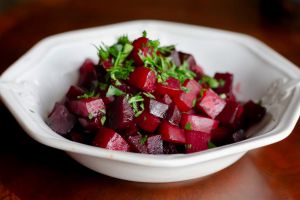 White bowl with braised beets using a mix of red, striped and golden beets