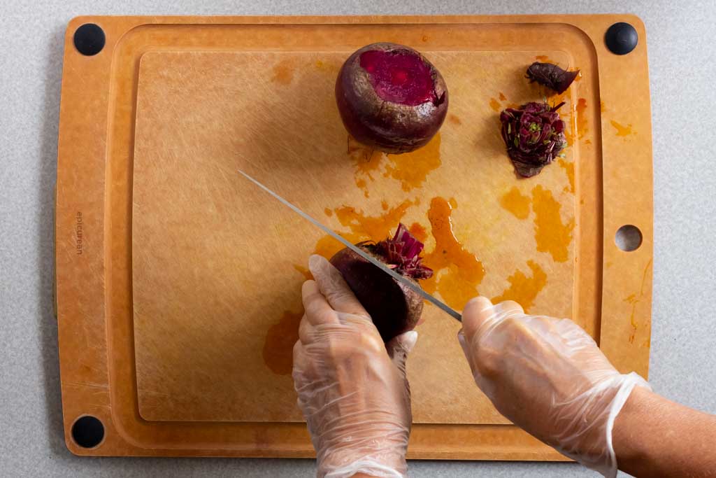 Cutting the stalk off beet with a chef knife on a cutting board