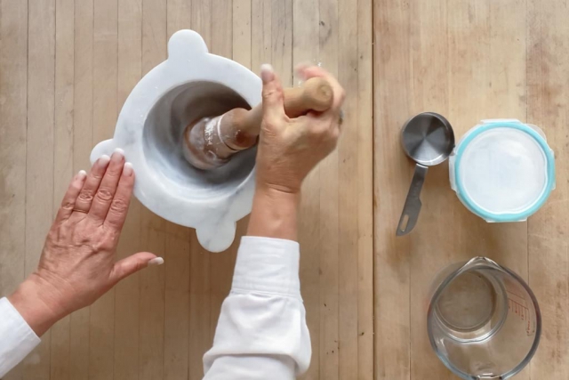 Scrubbing mortar with baking soda and water paste using the pestle