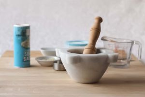 Marble mortar & pestle on a cutting board with prep tools and ingredients behind