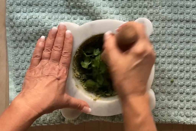 Parsley leaves in the marble mortar pressed by the pestle